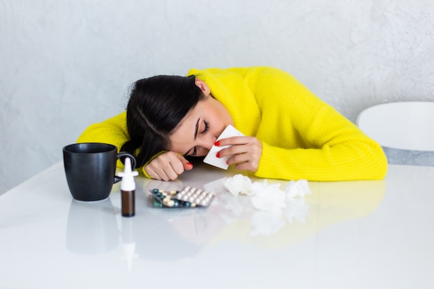 Sick woman with pills at kitchen table