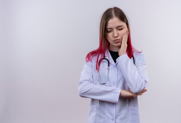 Sick young doctor girl wearing stethoscope medical robe putting her hand on aching tooth on isolated white background with copy space