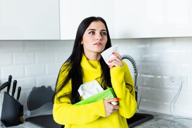 Free photo sick young woman blows her nose in the kitchen.