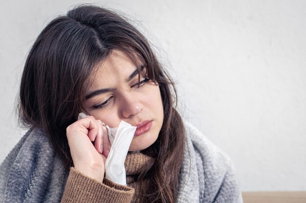 A sick young woman at home on the sofa with a cold copy space