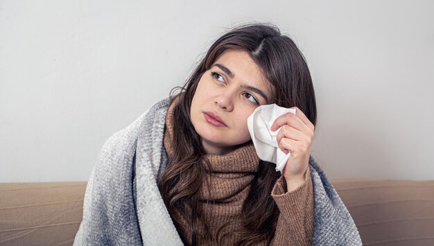 風邪をひいたソファで家にいる病気の若い女性