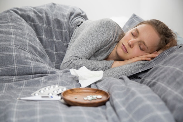 Sick young woman lying in bed, sleeping