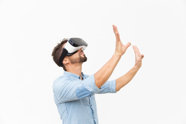 Side of bearded guy wearing VR goggles, touching air