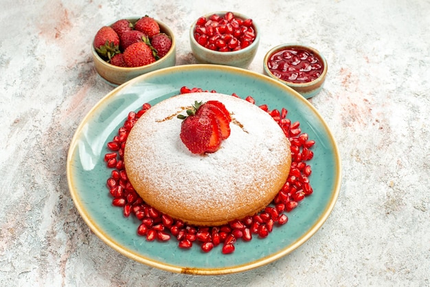 イチゴとザクロの食欲をそそるケーキとテーブルの上のベリーのボウルを食欲をそそる側面のクローズアップビュー