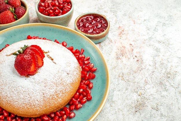 측면 클로즈업 보기 식욕을 돋우는 딸기와 석류 케이크 케이크와 테이블 위에 있는 딸기 그릇