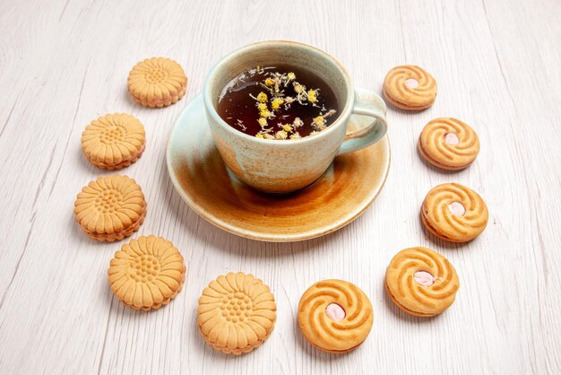 Side close-up view appetizing cookies herbal tea with and appetizing cookies around it on the white table