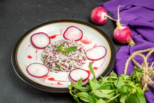 Side close-up view an appetizing dish plate of radish and sauce herbs and purple tablecloth