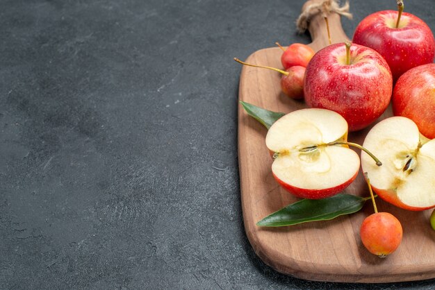 Side close-up view apples the appetizing berries and fruits on the wooden board