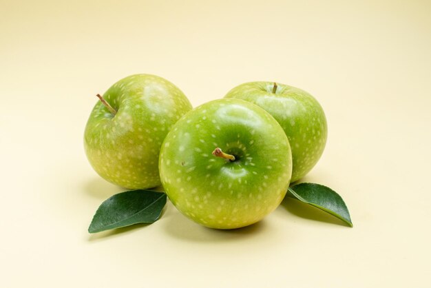 Side close-up view apples the appetizing green apples with leaves on the white surface
