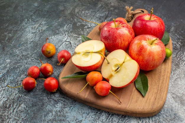 Боковой вид крупным планом яблоки разделочная доска с яблоками вишни с листьями
