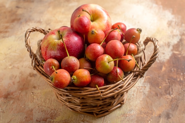 Боковой вид крупным планом ягоды, ягоды, яблоки в деревянной корзине на кремовом столе