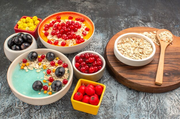 Side close-up view berries oatmeal on the board pomegranate seeds colorful berries yellow candies