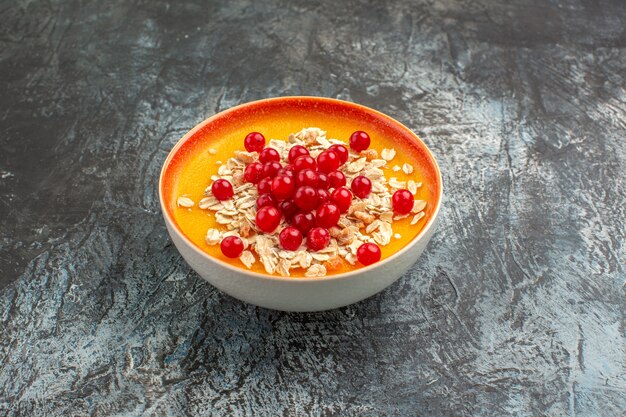 Side close-up view berries orange bowl of the appetizing red currants on the grey table