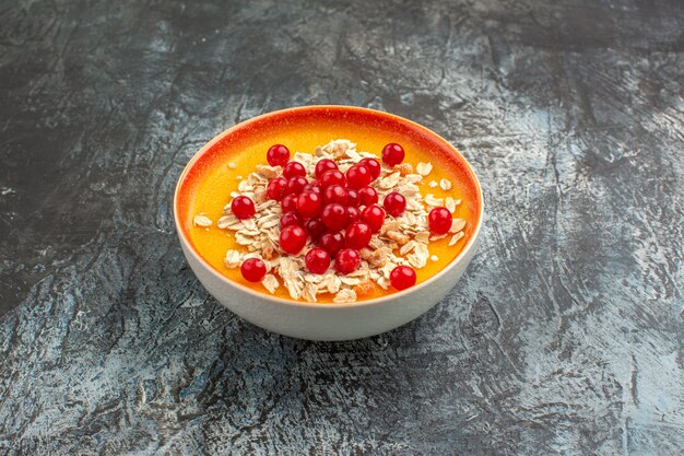 Боковой вид крупным планом ягоды оранжевой чаши аппетитной красной смородины на сером столе