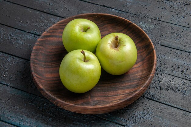 Side close-up view bowl of apples wooden bowl of green apples on dark table