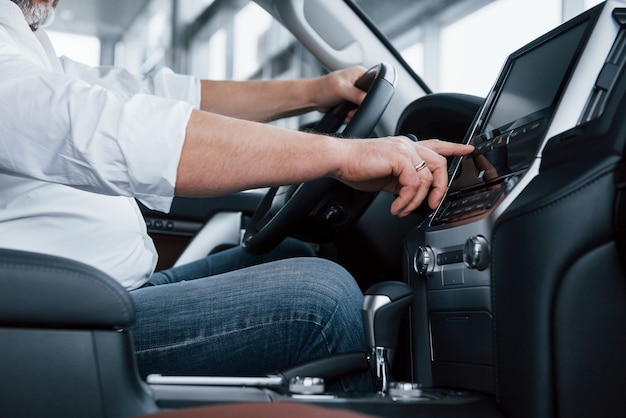 Free photo side close up view. businessman in official clothes sits in a luxury car and pushing the buttons on the music player