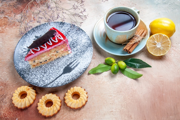 Side close-up view a cake an appetizing cake cookies a cup of tea cinnamon lemon