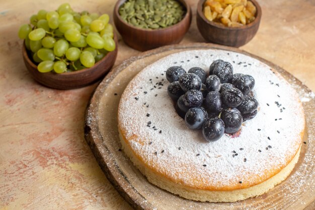 Free photo side close-up view a cake a cake on the board raisins green grapes pumpkin seeds
