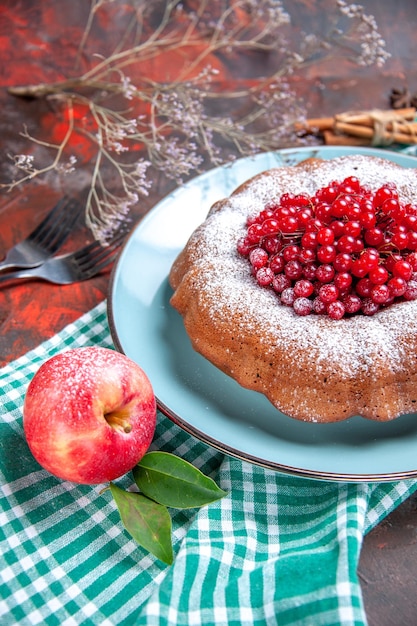 Side close-up view a cake a cake with red currants apple on the tablecloth forks cinnamon