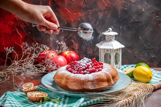 Side close-up view a cake a cake with red currants lemons apples spoon in the hand