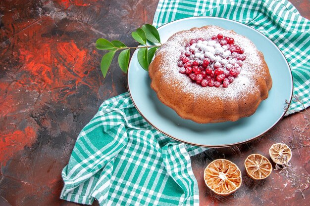 Side close-up view a cake a cake with red currants powdered sugar on the tablecloth lemon