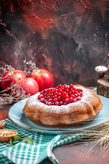 Vista ravvicinata laterale una torta una torta con ribes rosso sulla tovaglia tre mele spighe di grano