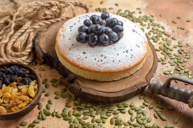 Side close-up view a cake raisins in the bowl a cake with black grapes pumpkin seeds rope