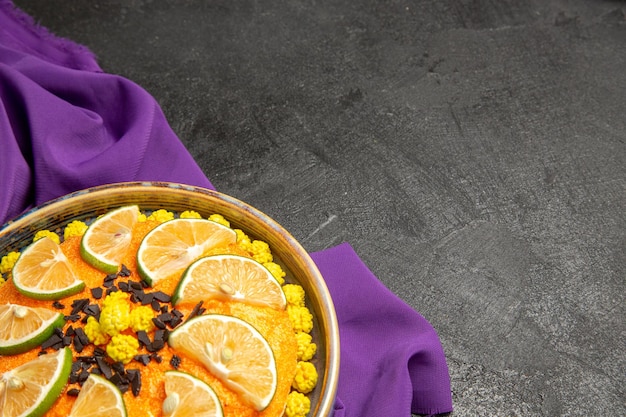 紫色のテーブルクロスにオレンジのスライスとケーキのレモンプレートと側面のクローズアップビューケーキ
