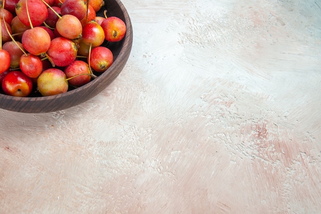 Free photo side close-up view cherries brown bowl of the appetizing cherries on the cream-grey table