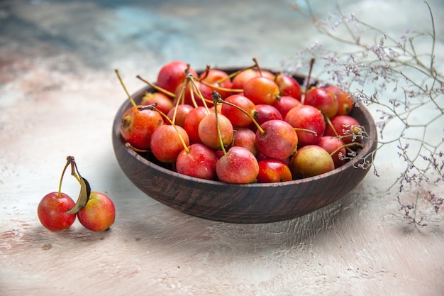 Side close-up view cherries cherries in the wooden bowl next to the tree abranches