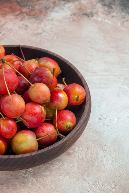 Side close-up view cherries wooden bowl of the appetizing cherries on the cream-grey table