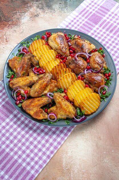 Side close-up view chicken plate of chicken potatoes herbs onion pomegranate on the tablecloth