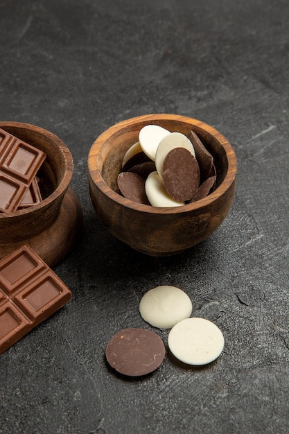 Вид сбоку крупным планом шоколадные деревянные миски аппетитного шоколада на темном столе