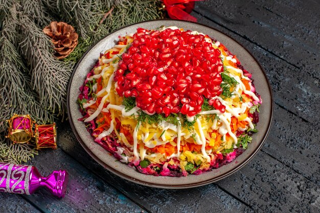 Side close-up view Christmas dish Christmas dish with pomegranate and spruce branches with Christmas tree toys