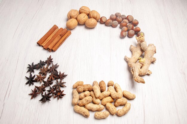 Side close-up view cinnamon sticks nuts different kinds of nuts and cinnamon sticks are laid out in a circle on the white table