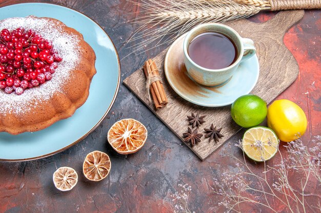 Вид сбоку крупным планом чашка чая торт с ягодами чашка чая корица цитрусовые