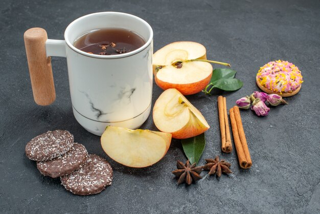 Вид сбоку крупным планом чашка чая, печенье, чашка травяного чая, кусочки яблока, палочки корицы