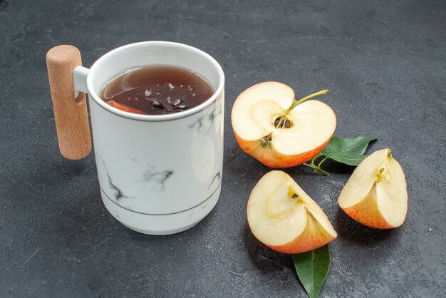 Side close-up view a cup of tea a cup of herbal tea with cinnamon sticks peeled apple