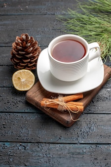 Side close-up view a cup of tea a cup of tea next to the lemon cones cinnamon sticks and christmas tree branches