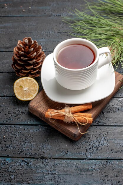 Side close-up view a cup of tea a cup of tea next to the lemon cones cinnamon sticks and Christmas tree branches