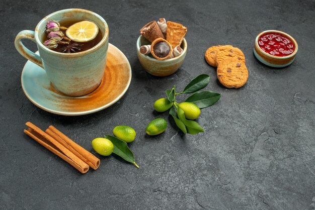 Side close-up view a cup of tea a cup of tea with lemon cinnamon citrus fruits cookies jam