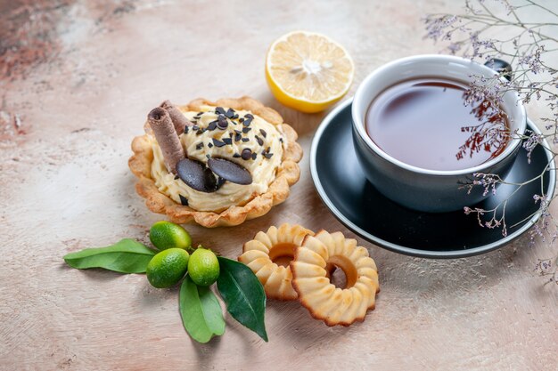 Side close-up view a cup of tea cupcake a cup of tea cookies citrus fruits