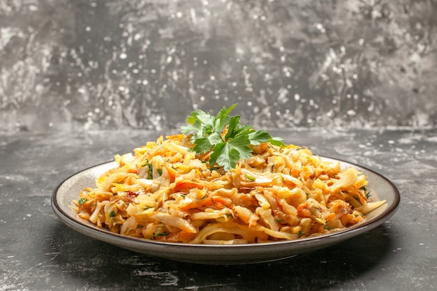 Side close-up view dish the appetizing dish of cabbage carrots herbs on the dark background