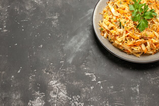 Side close-up view dish dish of the appetizing carrots cabbage and herbs on the white plate