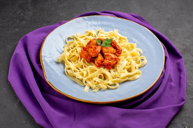 Foto gratuita piatto vista ravvicinata laterale sulla tovaglia piatto di pasta con sugo e carne sulla tovaglia viola sul tavolo