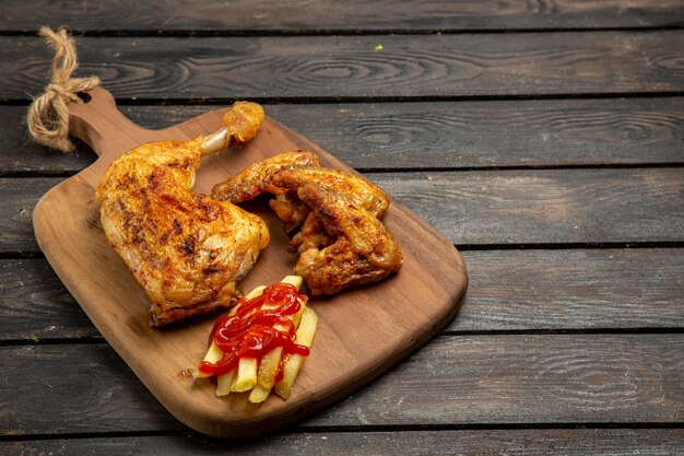 Side close-up view french fries french fries and appetizing chicken bowl of ketchup on the cutting board on the wooden table