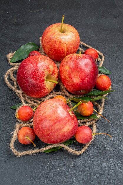 Вид сбоку крупным планом фрукты аппетитные яблоки вишня с листьями веревки
