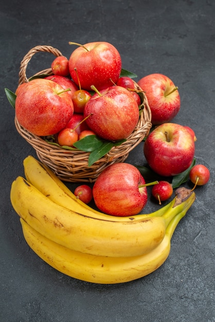 Free photo side close-up view fruits bananas wooden basket of apples and cherries