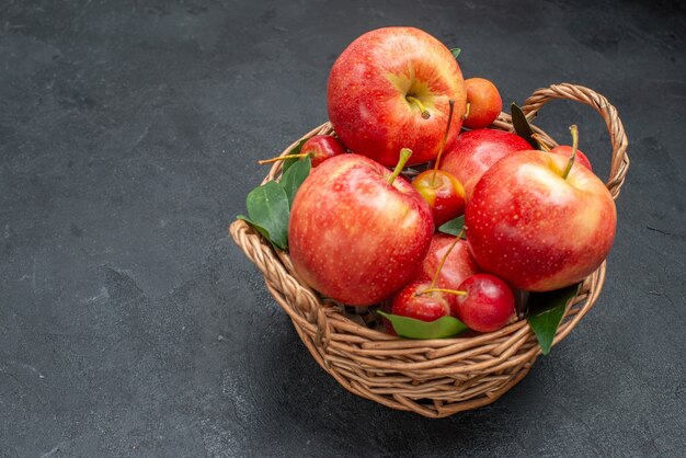 Боковой вид крупным планом, корзина с фруктами и аппетитными яблоками и вишнями