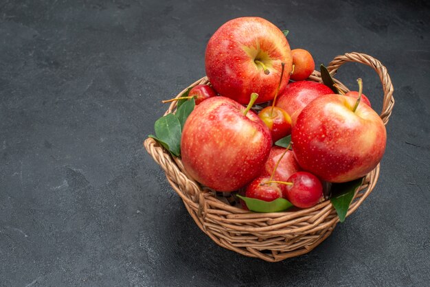 Side close-up view fruits basket of the appetizing apples and cherries